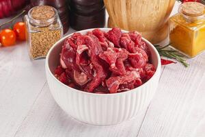 Raw meat in a bowl on a white table photo