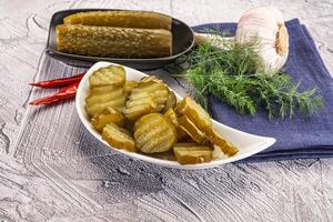 A bowl of pickles and a plate of garlic photo