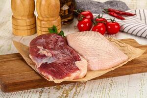 A cutting board with a raw chicken and tomatoes photo