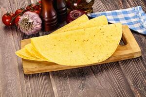 A tortilla on a cutting board with tomatoes and spices photo