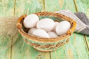 White eggs in a basket on a wooden table photo