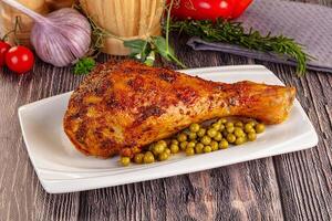 A large piece of chicken with peas and tomatoes photo