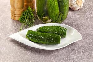 A jar of pickles and a plate with cucumbers photo