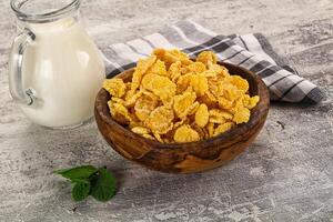 Corn flakes and milk in a wooden bowl on a rustic background photo