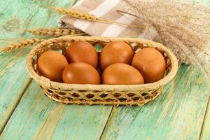 Fresh eggs in a basket on a wooden table photo