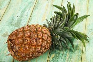A pineapple is sitting on a wooden table photo