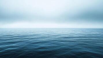 The ocean is calm and clear, with no visible waves. The sky is overcast, giving the scene a peaceful and serene atmosphere photo