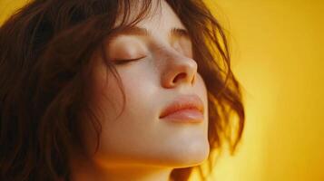 Portrait of a serene young woman with closed eyes, bathed in warm light against a vibrant golden background. She exudes peacefulness. photo