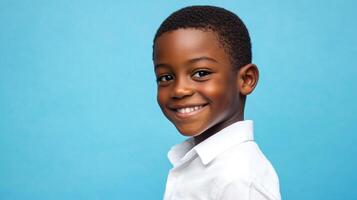 A smiling young boy poses against a blue background. He has a kind face and is wearing a button down shirt. He seems happy and at ease. photo