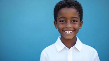 A happy young boy in a white shirt smiles brightly against a vibrant blue background, radiating joy and innocence in a studio setting. photo