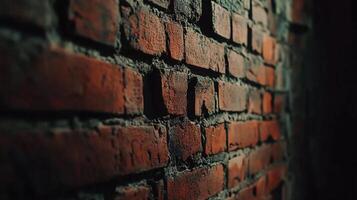 Close up view of a weathered red brick wall with dark, shadowed areas. The bricks have a rough texture, creating an aged backdrop. photo