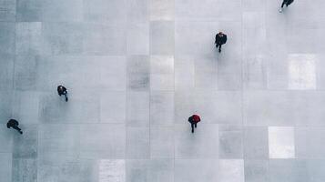 Overhead view of people walking on a tiled floor. People are spread apart and look tiny. Tiled floor is made of large square tiles. photo