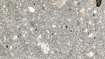 Detailed surface of a gray composite material speckled with small stones and fragments, creating a unique textured appearance. photo