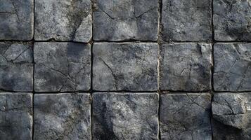 A stone tile floor is seen in a top-down shot. Each tile has cracks and is slightly varied in texture giving it a unique appearance. photo