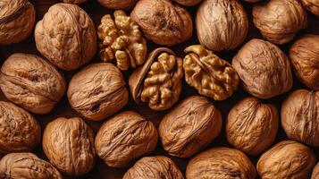 Top-down view showcases a collection of walnuts, some cracked open to reveal the golden nut inside on a neutral surface. photo