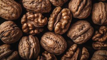Pile of fresh walnuts with intricate shell textures, perfect for a healthy snack or delicious recipe ingredient, on a dark background. photo