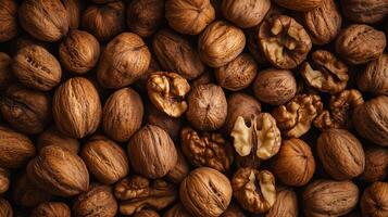 A pile of walnuts in their shells and cracked open, showcasing the light-colored walnut meat inside. Top-down perspective. photo