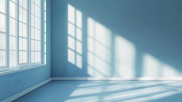 Sunlight streams into an empty blue room through a large window, creating geometric patterns of light and shadow on the wall and floor. photo