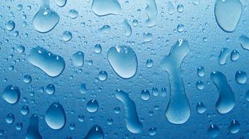 An abstract close-up shows scattered water droplets resting on a blue surface. The droplets range in size and shape, showcasing condensation. photo
