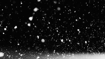 A dynamic black and white image captures the ethereal dance of falling snow against a dark backdrop, creating a serene winter scene. photo