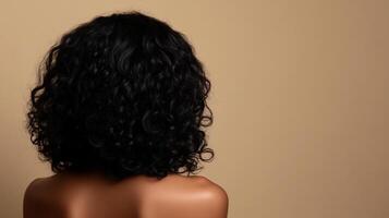 A portrait showcases an individual with voluminous, curly hair, styled with a focus on shape and texture against a neutral backdrop. photo