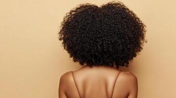 Close-up of a person with dark, curly hair. Focus on texture and shape, set against a neutral backdrop, emphasizing natural beauty. photo