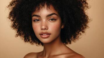 Striking beauty portrait of a young woman with naturally curly hair and freckles set against a neutral background. Radiant complexion. photo