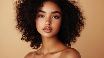 Portrait of a woman with curly dark hair, brown eyes, and freckles. She has neutral makeup and a confident expression on a neutral background. photo