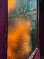 Christmas tree with lights reflecting on foggy window during winter. Warm orange Christmas lights reflecting foggy window, cozy and festive atmosphere, cold winter day, sense of magic and celebration photo