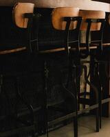 Brown vintage bar stools. Row of vintage bar stools with brown leather seats, placed in front of dark textured wall, creating nostalgic and stylish atmosphere in bar or restaurant setting photo