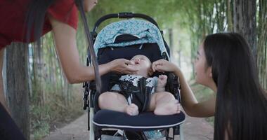 Selective focus shot, Two young Asian women playing with little boy in a baby stroller outside a coffee shop. A relaxing atmosphere with a warm moment. photo