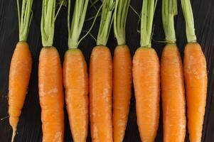 Fresh Organic Carrots with Green Tops Arranged on a Dark Wooden Background photo