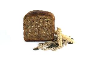 A nutritious slice of multigrain bread featuring an array of seeds and a single sprig of wheat. photo