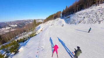 Smooth FPV flight over snowy mountain slope with people skiing and snowboarding. video
