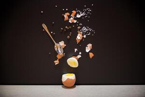 Simple breakfast. Boiled egg with spices and shell on black background photo