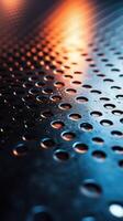 Textured metallic surface with droplets reflecting warm light during evening hours photo
