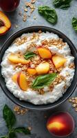 Bowl of cottage cheese topped with fresh peach slices, granola, and basil leaves on a textured surface photo