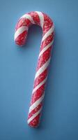Candy cane decorated with red and white stripes on a blue background showcasing holiday spirit and festive cheer photo