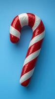 Bright red and white striped candy cane placed on a blue background during the holiday season photo