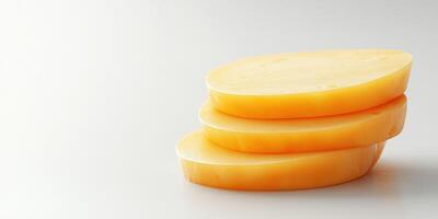 Sliced cheese stacked on a plain surface showcasing texture and color photo