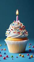 Colorful cupcake with a lit candle against a vibrant blue background and scattered candy on the surface photo