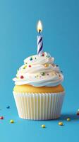 Decorated cupcake with sprinkles and a lit candle against a blue background photo