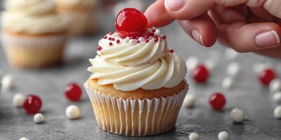 Decorating a delightful cupcake with frosting and cherry on a festive table setting photo