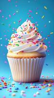 Colorful cupcake topped with fluffy white icing and vibrant sprinkles against a blue background photo