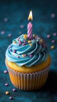 Colorful birthday cupcake with blue frosting and a single candle on a decorative background photo