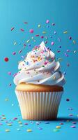Colorful cupcake with sprinkles floating against a bright blue background in a playful dessert scene photo