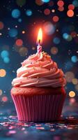 Colorful cupcake with a lit candle and festive bokeh lights in the background photo