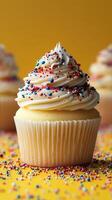 Sweet cupcakes topped with creamy frosting and colorful sprinkles on a vibrant yellow background photo