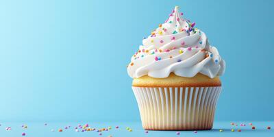 Colorful cupcake topped with swirls of frosting and sprinkles against a bright blue background photo