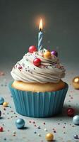 Colorful cupcake with a lit candle and confetti on a gray background for birthday celebration photo